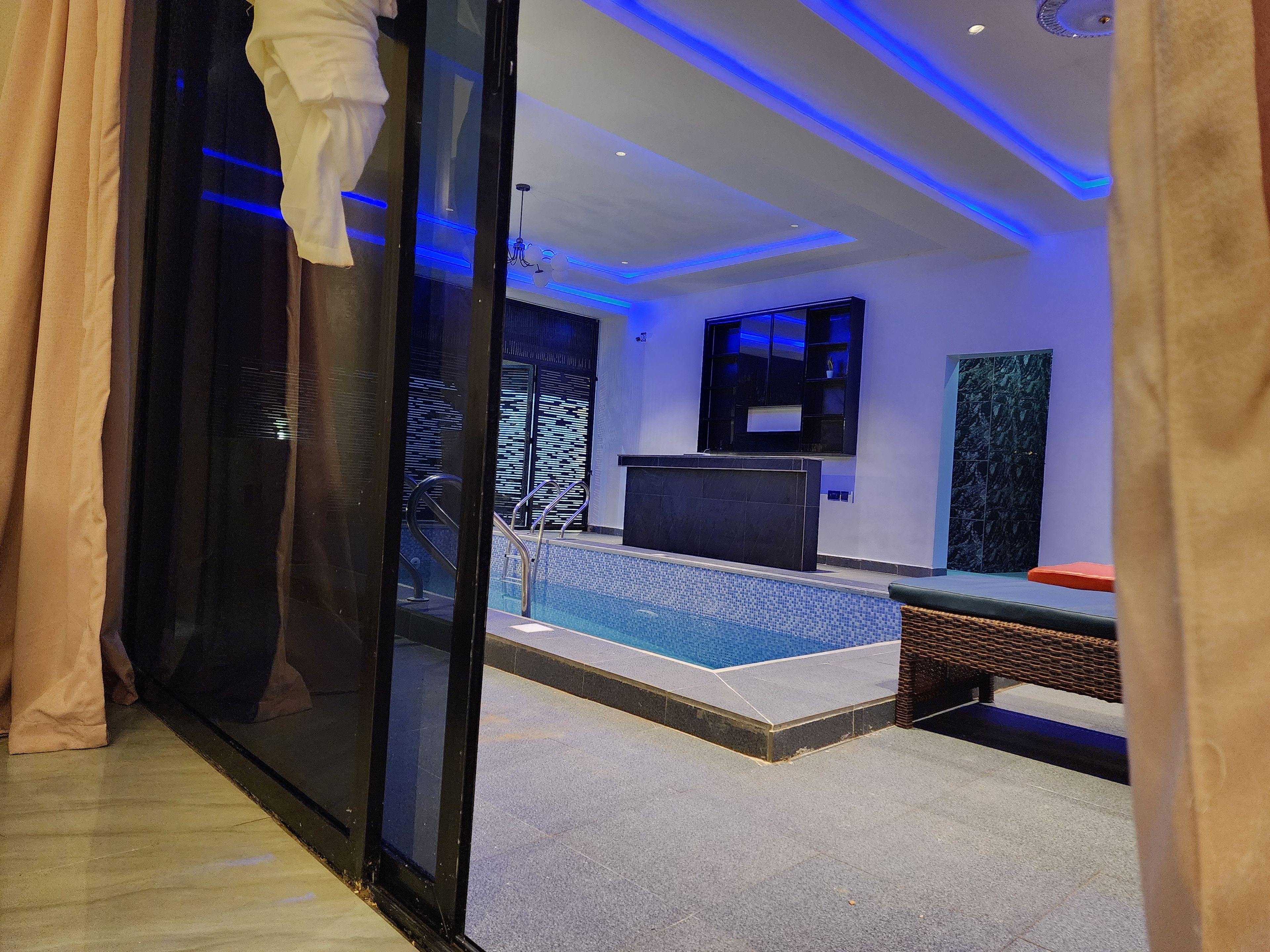 Habitación de hotel moderna con piscina, un amplio ventanal y televisor.
