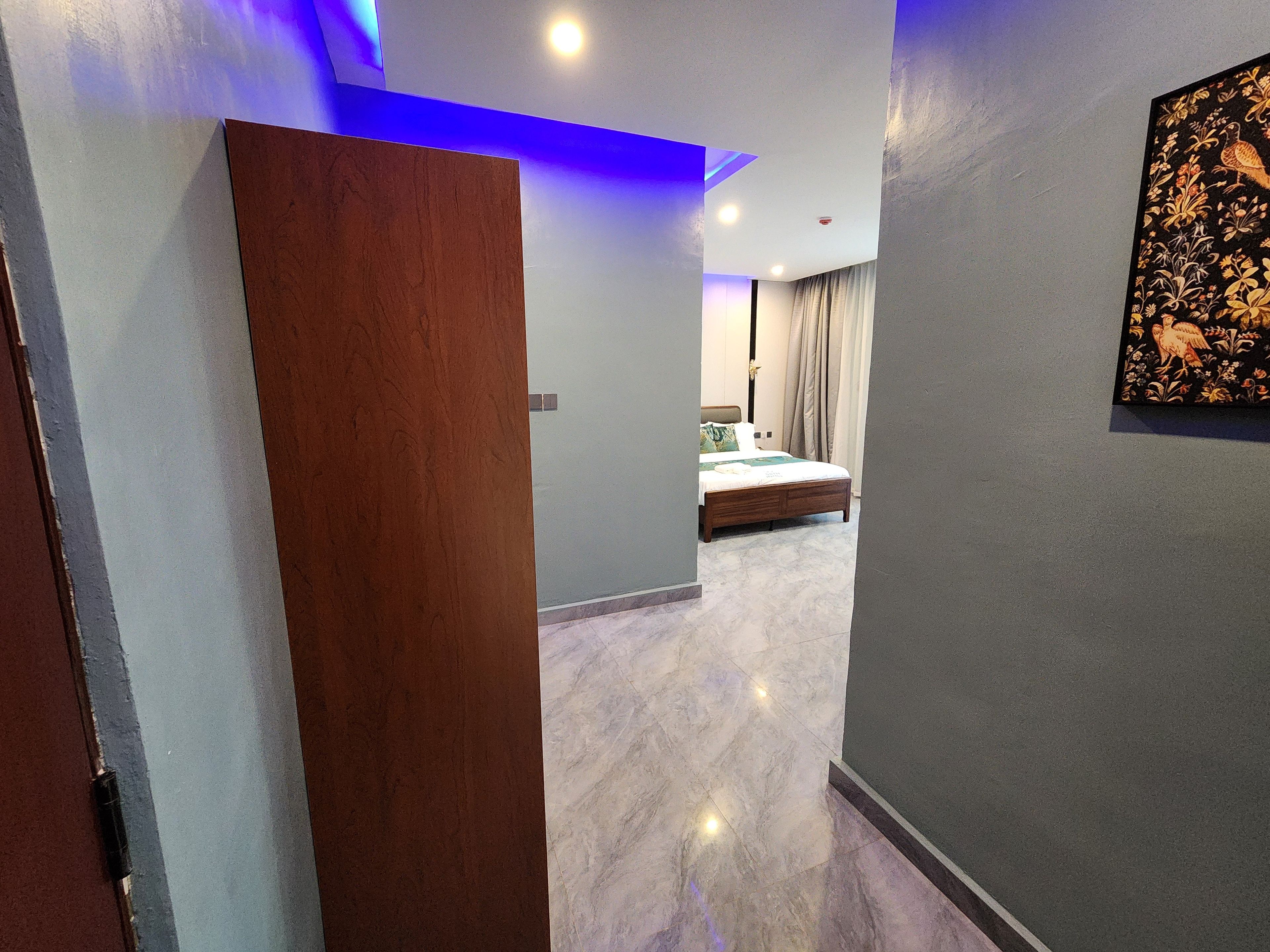 A modern hotel room with a bed, a nightstand, and a painting on the wall.