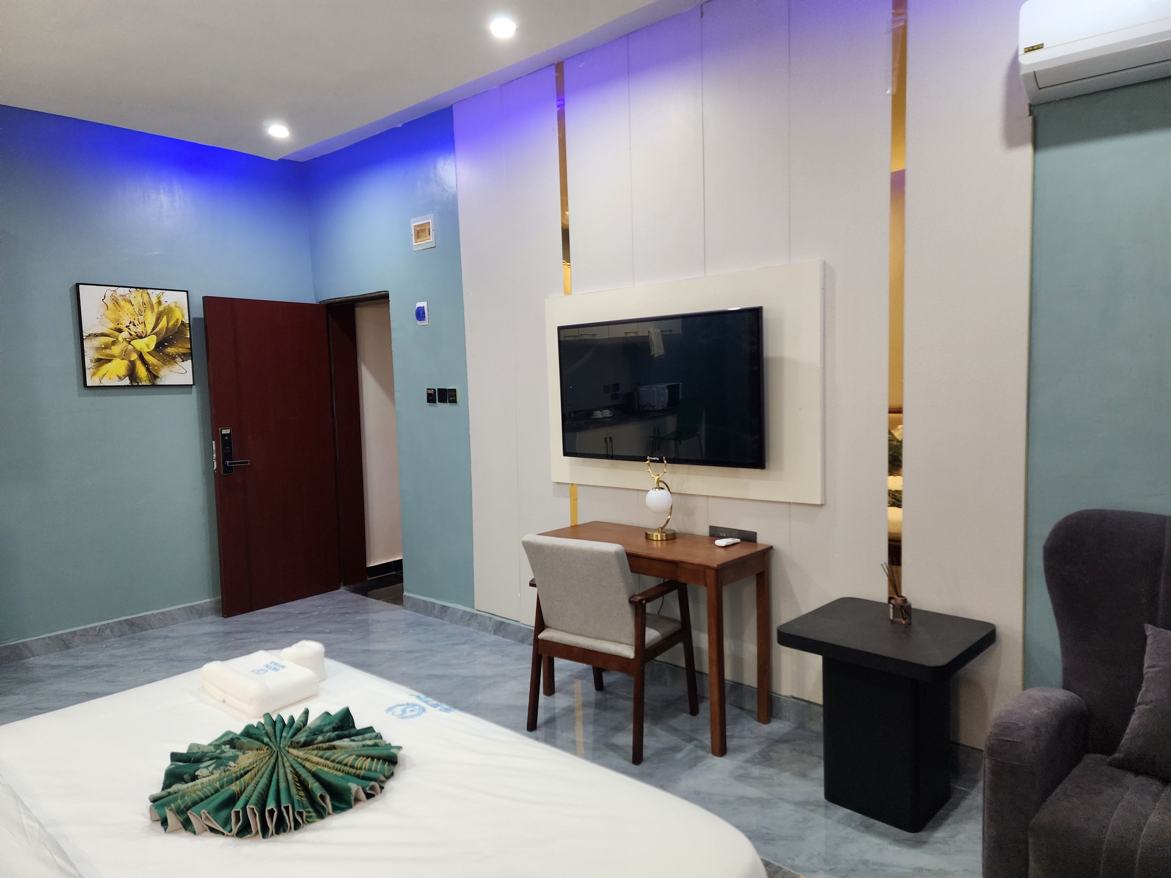 A hotel room with a bed, a desk with a chair, a television, and a sofa.