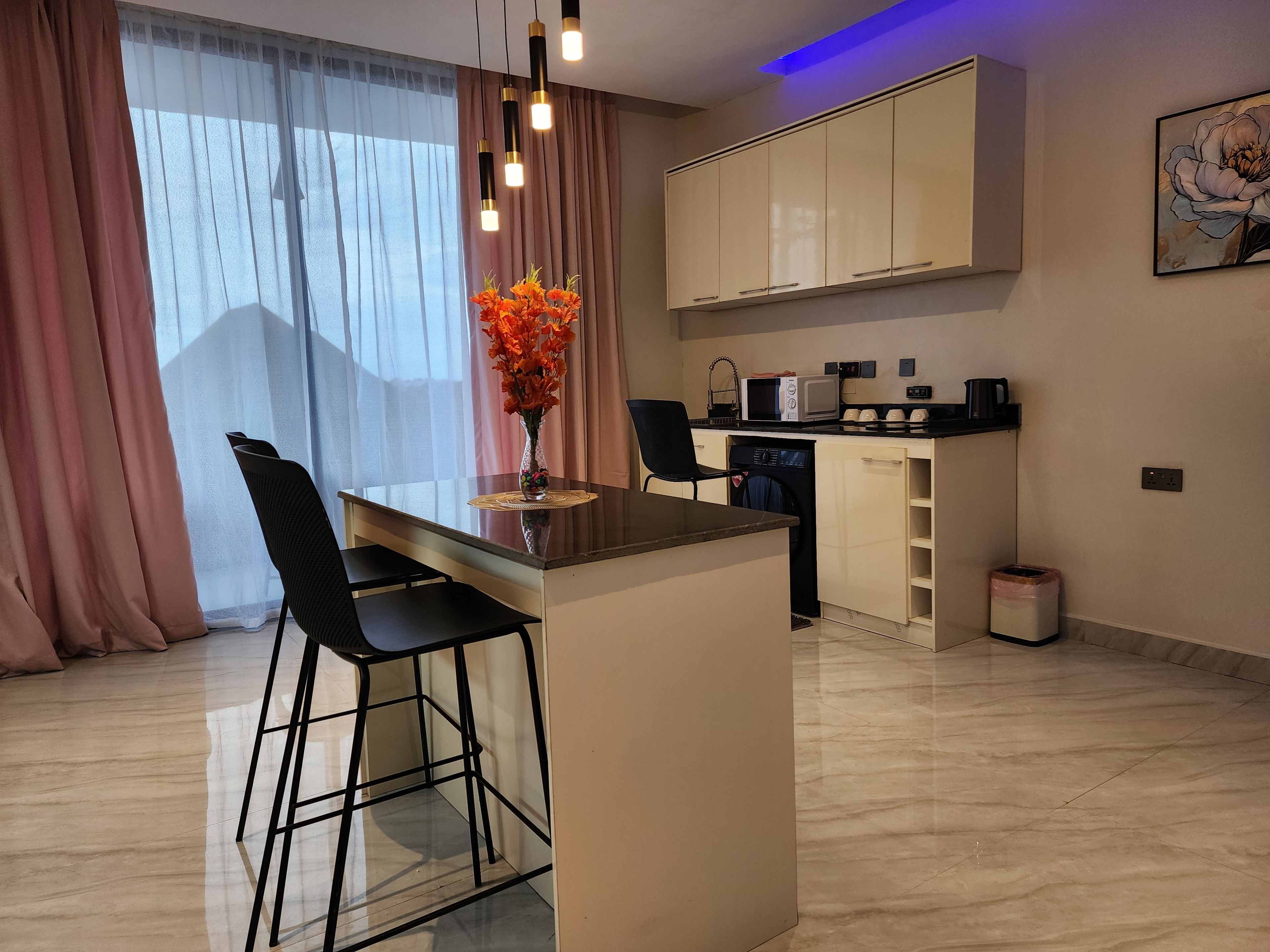 A modern kitchen with a built-in island, bar stools, a microwave, and a coffee machine.