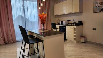 A modern kitchen with a built-in island, bar stools, a microwave, and a coffee machine.
