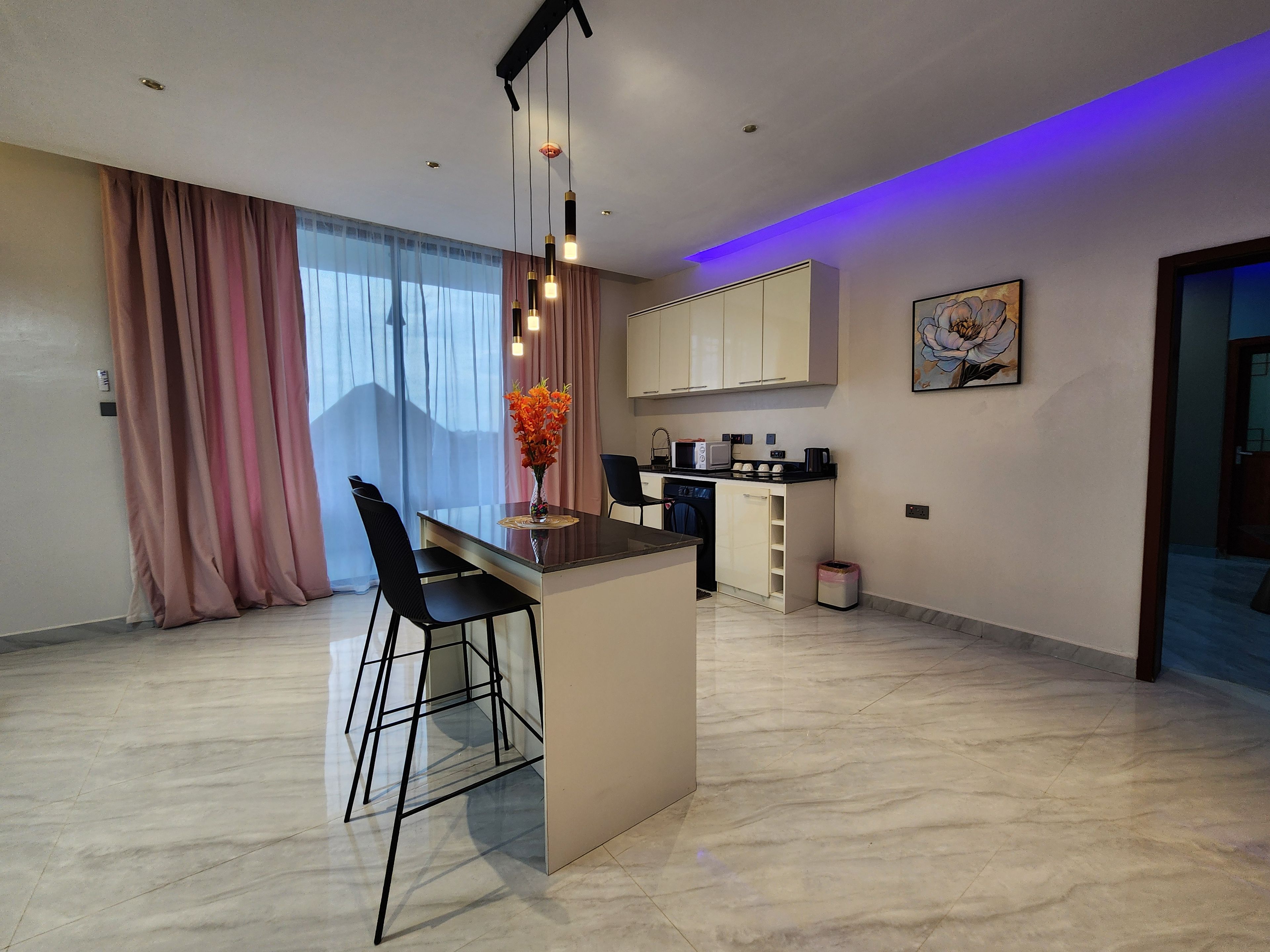 Una cocina moderna con una isla central, taburetes de bar y un comedor.