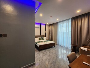 A modern hotel room with a bed, a seating area, and a large window with curtains.