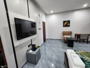 A modern living room with a flat-screen TV, a sofa, a coffee table, and a dining area with chairs. - Sethhotel Apartment & Suite (Asaba)