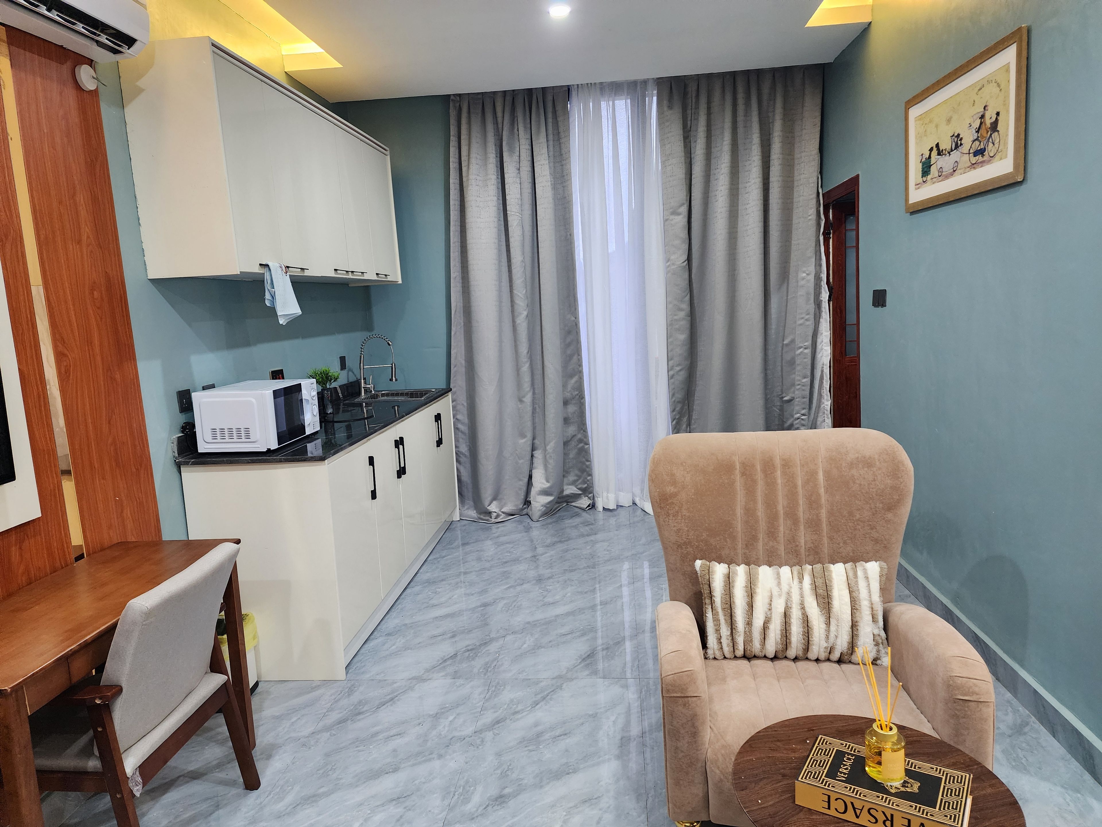 Un espacio habitable compacto con kitchenette, sofá y zona de comedor.