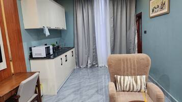 Un espacio habitable compacto con kitchenette, sofá y zona de comedor.