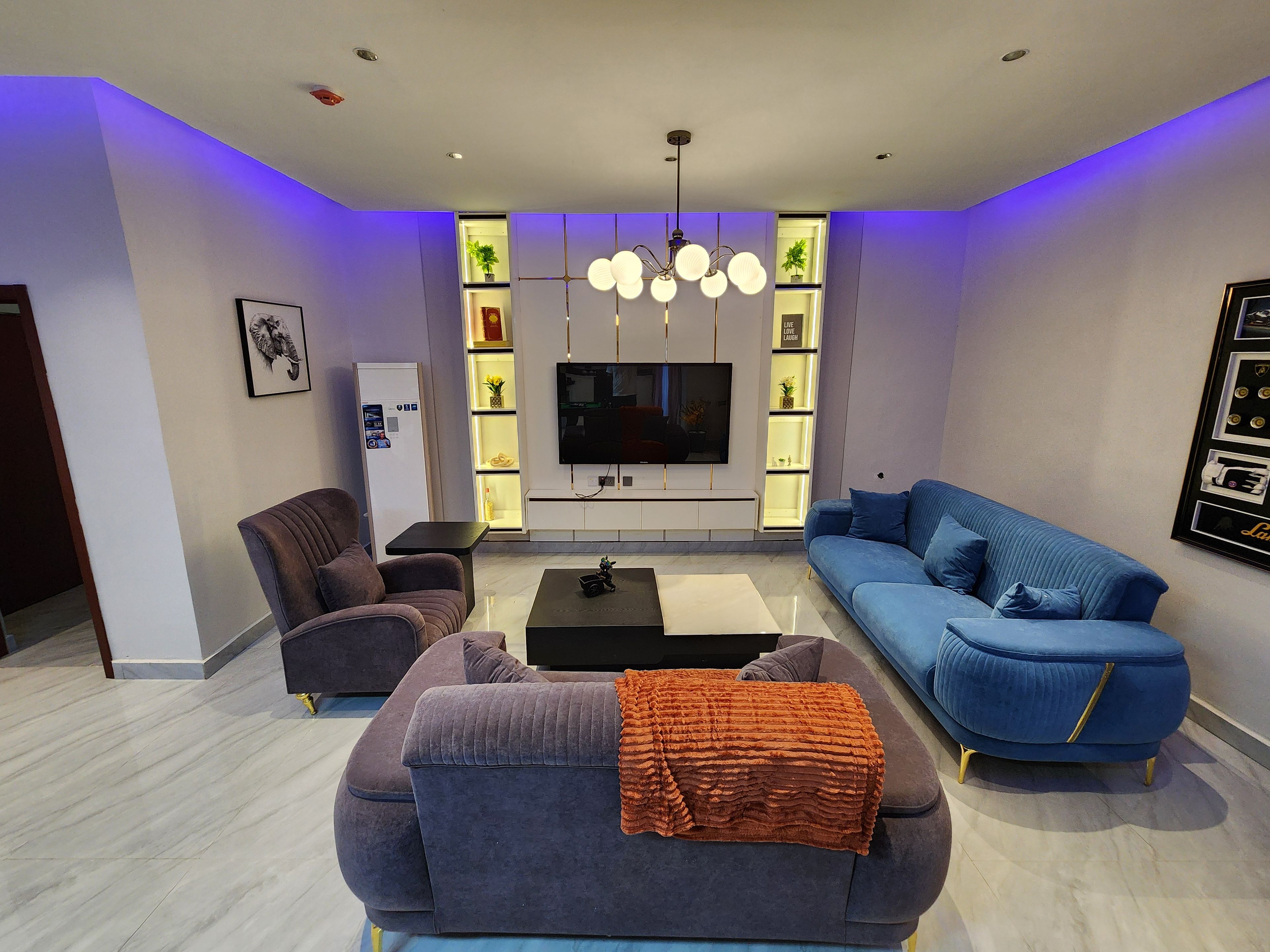 A modern living room with a sofa, armchair, coffee table, and a TV.