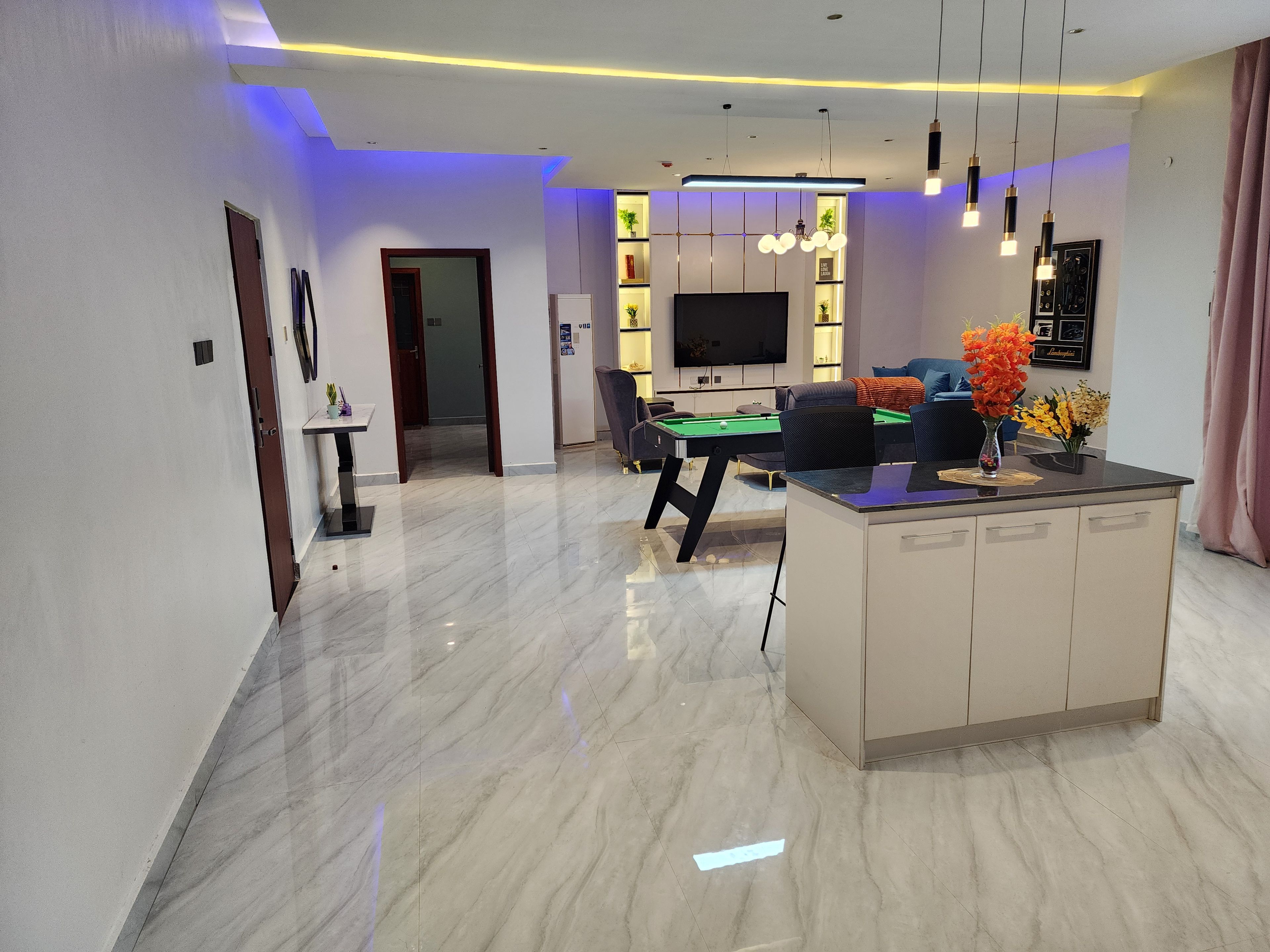 Una sala de estar moderna con mesa de billar, sofá y televisor.