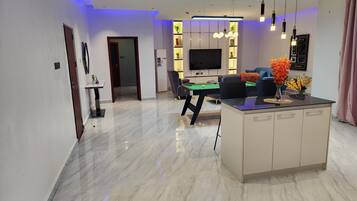 Una sala de estar moderna con mesa de billar, sofá y televisor.