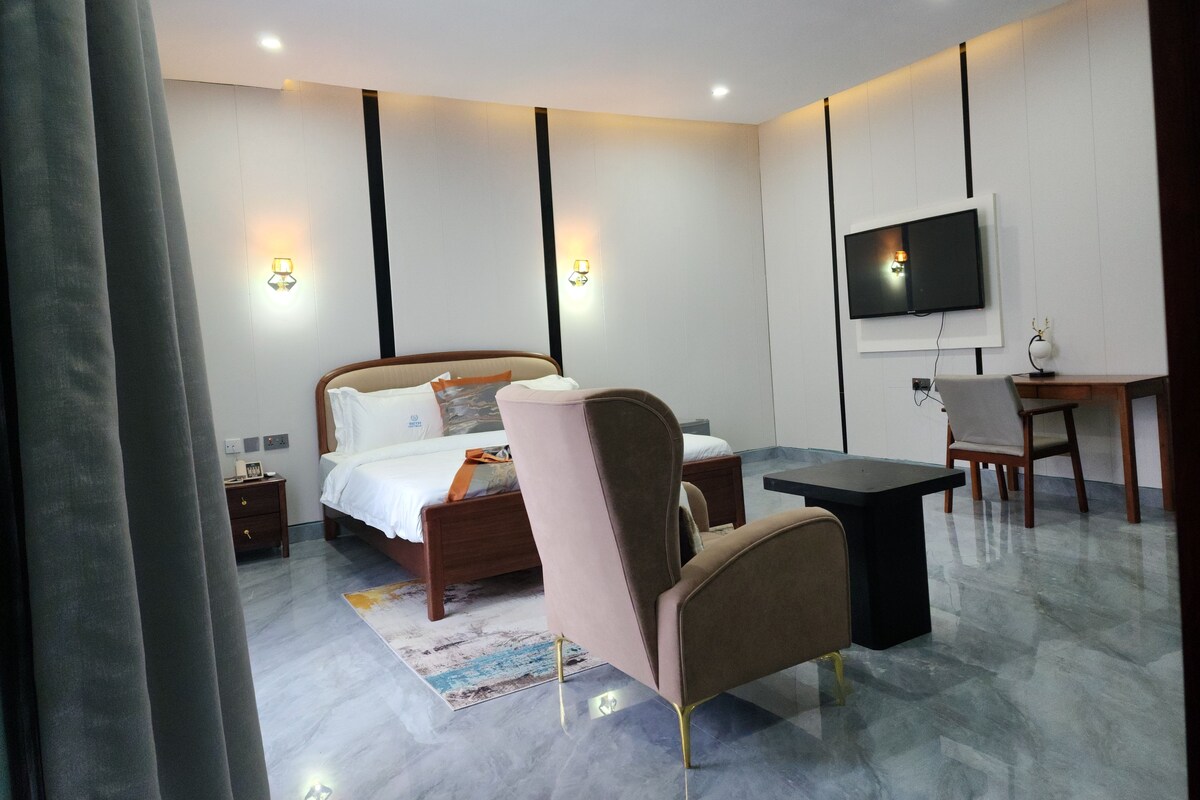 Una habitación de hotel moderna con una cama, un escritorio, una silla, un televisor y una mesita.