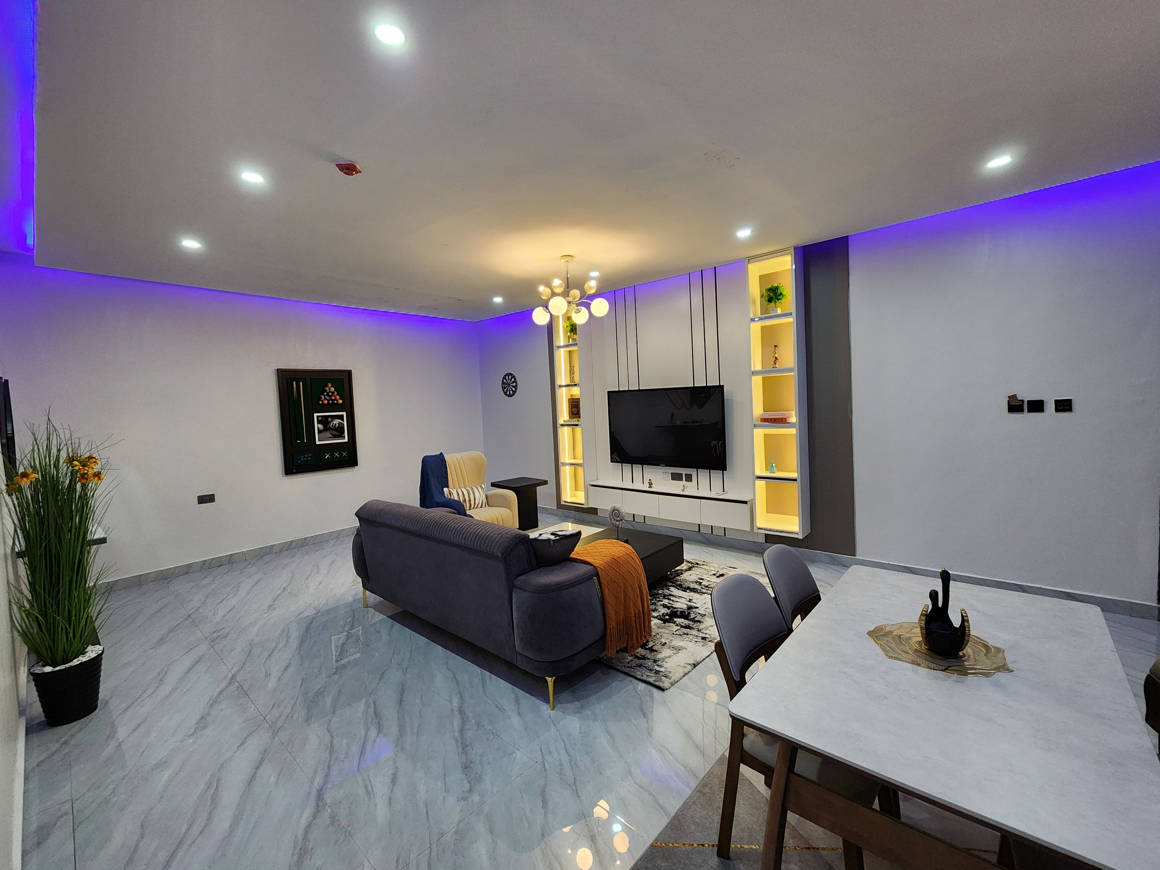 Una sala de estar moderna con un sofá, una mesa de comedor y un televisor montado en la pared.