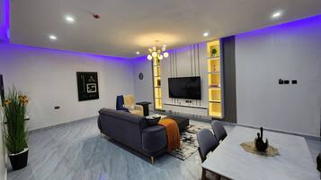Una sala de estar moderna con un sofá, una mesa de comedor y un televisor montado en la pared.