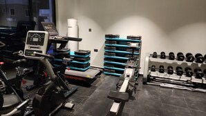 Een fitnessruimte met trainingsapparatuur, gewichtstapels en dumbbells.