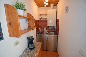 A compact kitchen with a stove, sink, and a coffee maker. - First floor, central location, about 150 m from the sandy beach (Baltic Sea), accommodates up to 4 people (Juliusruh)