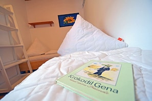 En snyggt bäddad säng med en kudde och en bok med titeln ”Krokodil Gena” på den.