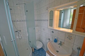 Ein Badezimmer mit Dusche, Toilette, Waschbecken und einem Spiegel darüber.