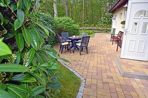 Eine Terrasse mit Ziegelboden, einem Tisch und Stühlen sowie einer weißen Tür.
