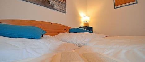 A bed with a book open, a nightstand with a lamp, and a painting on the wall.