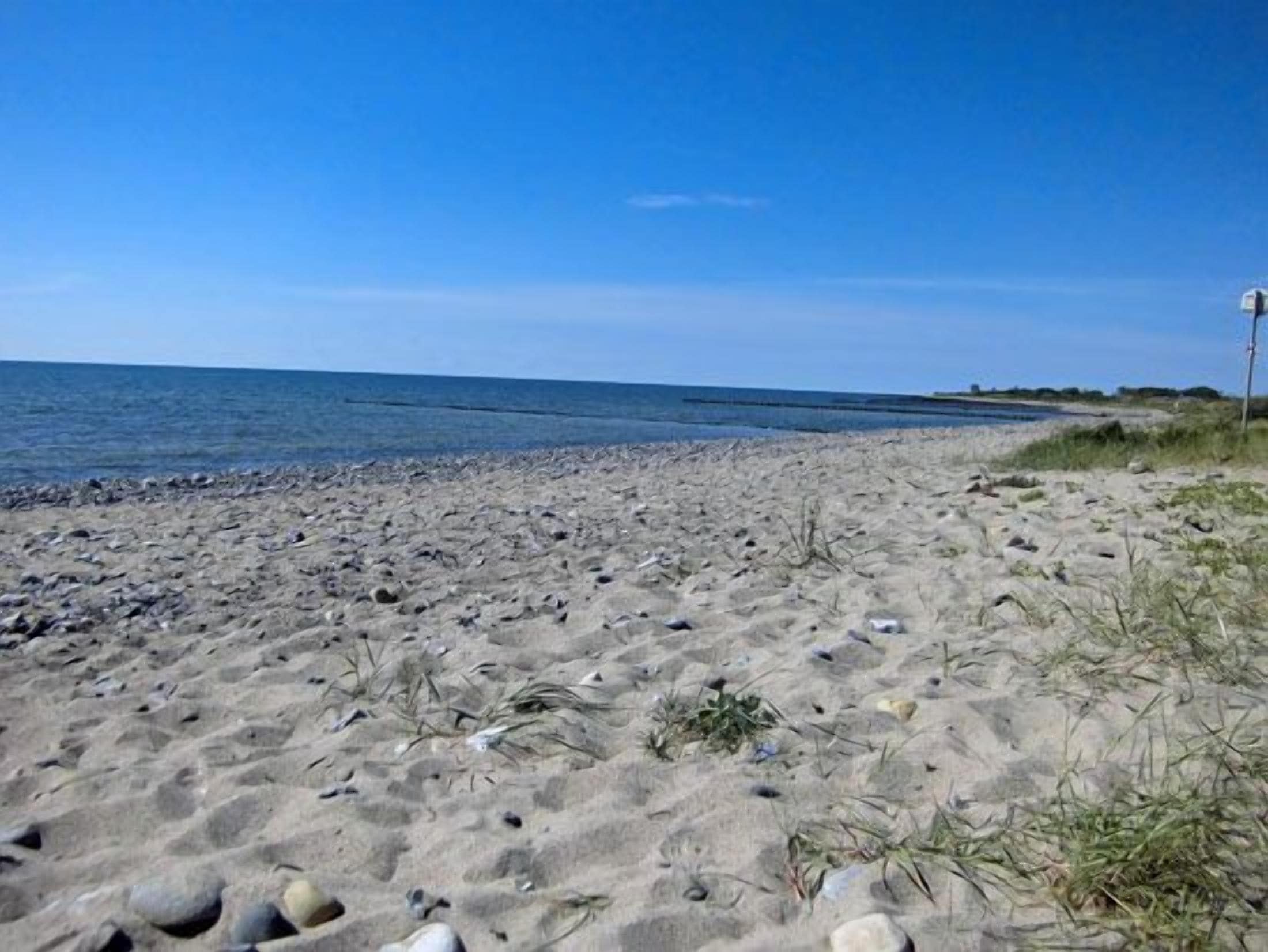 Ein Strand mit blauem Himmel, Sandstrand und ruhiger See.