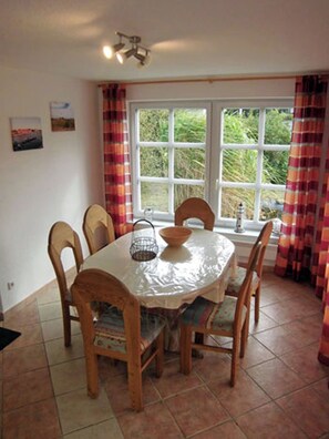 A dining area with a round table, chairs, and a window with curtains. - Quiet location with a terrace, about 6 km from the Baltic Sea, about 800 m from the Bodden (Wiek)