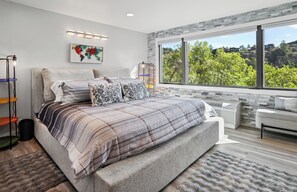 Un dormitorio moderno con una cama grande, vistas a zonas verdes y un mapa mundial en la pared.