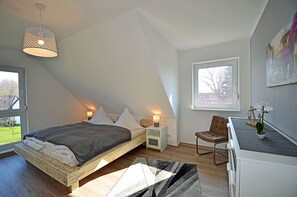 A bedroom with a sloped ceiling, a bed, bedside lamps, a chair, a desk, and a window with a view. - 800 meters to the beach, 3 bedrooms, sleeps up to 6, Wi-Fi, washing machine (Breege)