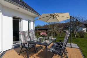 An outdoor patio with a table set for four, surrounded by cushioned chairs, a large umbrella, and a flower vase. - 800 meters to the beach, 3 bedrooms, sleeps up to 6, Wi-Fi, washing machine (Breege)