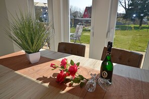 A dining table with a potted plant, a bottle of champagne, and a glass. - 800 meters to the beach, 3 bedrooms, sleeps up to 6, Wi-Fi, washing machine (Breege)