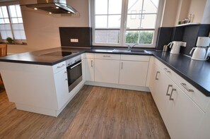 A modern kitchen with a central island, built-in oven, and a window providing natural light. - Only about 750 meters from the beach, fireplace, Wi-Fi, washing machine, dryer, sleeps up to 6 people (Breege)