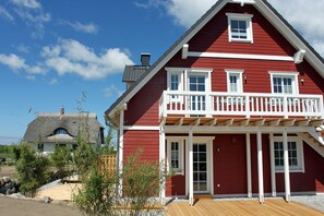 A red building with a balcony and a wooden deck. - Only about 750 meters from the beach, fireplace, Wi-Fi, washing machine, dryer, sleeps up to 6 people (Breege)