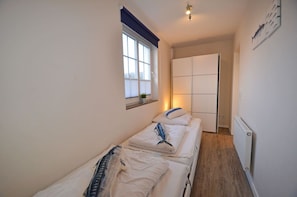 A narrow hotel room with two single beds, a window with blinds, a radiator, and a door leading to another room. - Only about 750 meters from the beach, fireplace, Wi-Fi, washing machine, dryer, sleeps up to 6 people (Breege)