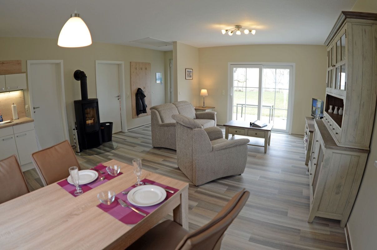 A dining area with a table set for two, a sofa, and a fireplace.