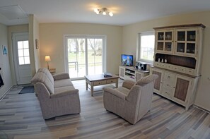 A living room with a sofa set, a coffee table, a television, and a cabinet with glass doors. - Very quiet location with a large sun terrace, fenced-in property (Dranske)