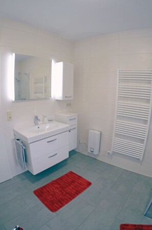 A bathroom with a white sink, mirror, and towel rack. - Very quiet location with a large sun terrace, fenced-in property (Dranske)