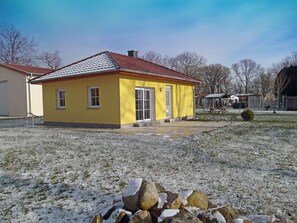 A yellow house with a red roof, a front door, and a small porch. - Very quiet location with a large sun terrace, fenced-in property (Dranske)