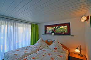 A bedroom with a bed, a window with a view of greenery, a clock, and a bedside lamp. - Vacation home in a very quiet location with a view of the Bodden; pets allowed; 2 bedrooms (Breege)