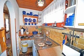 A kitchen with a wooden ceiling, a sink, a stove, and various kitchen utensils. - Vacation home in a very quiet location with a view of the Bodden; pets allowed; 2 bedrooms (Breege)