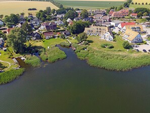 An aerial view of a riverside village with houses, a small bridge, and a boat dock. - Vacation home in a very quiet location with a view of the Bodden; pets allowed; 2 bedrooms (Breege)