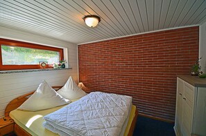 A room with a bed, a window with a view, a brick wall, and a wooden ceiling. - Vacation home in a very quiet location with a view of the Bodden; pets allowed; 2 bedrooms (Breege)