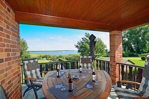 A wooden deck with a table set for dining, overlooking a body of water. - Vacation home in a very quiet location with a view of the Bodden; pets allowed; 2 bedrooms (Breege)