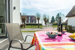 Ein Essbereich im Freien mit einem Tisch für zwei Personen, einer Weinflasche und Schalen mit Essen.