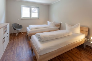 Una habitación con tres camas individuales, una silla y un escritorio.