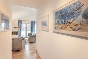 Un pasillo con chimenea, un sofá y un cuadro de pájaros en la pared.