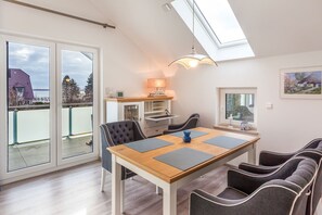 Un comedor con una mesa, sillas, una lámpara y vistas a través de amplios ventanales.