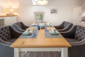A dining area with a wooden table, cushioned chairs, and a lamp. - 1,800 m from the beach, 2 bedrooms, sleeps up to 4, Wi-Fi, washing machine, sauna (Breege)