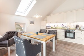 A modern kitchen with white cabinets, a built-in oven, and a skylight above the dining area. - 1,800 m from the beach, 2 bedrooms, sleeps up to 4, Wi-Fi, washing machine, sauna (Breege)