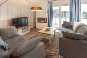A modern living room with a flat-screen TV, a fireplace, and a sofa set. - 1,800 m from the beach, 2 bedrooms, sleeps up to 4, Wi-Fi, washing machine, sauna (Breege)