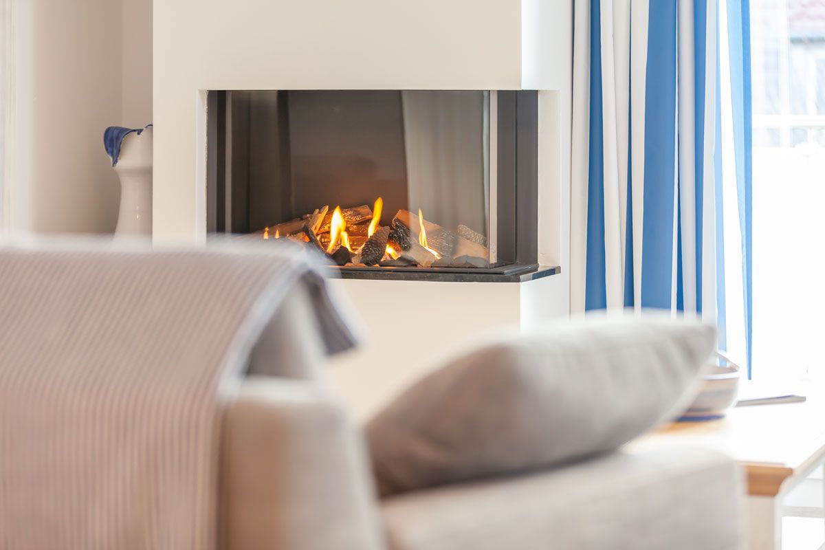 A living room with a fireplace, a sofa, and a window with curtains.