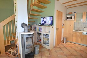 Ein Wohnbereich mit Kamin, Fernseher und Küche.
