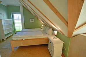 Un dormitorio con una cama individual, una mesita de noche, un aparador y una ventana con persianas.